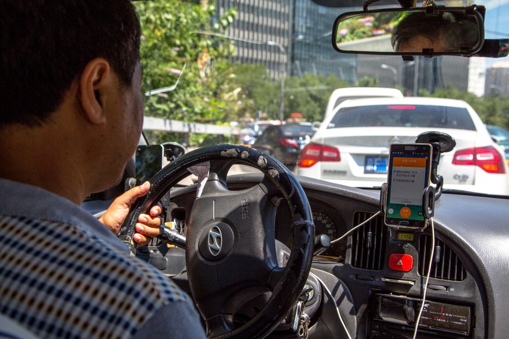 A taxi driver is using Didi Dacha App while driving on the...