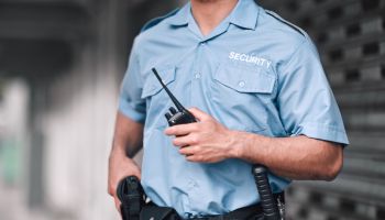 Security guard, safety officer and man with walkie talkie in hand on street for protection, patrol or watch. Law enforcement, focus and duty with a crime prevention male worker in uniform in the city