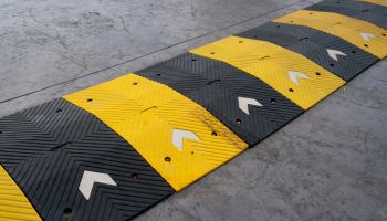 Speed bump on the road, yellow and black striped speed bump in asphalt road to slow down fast moving cars