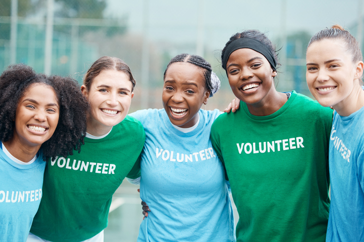 Happy women, portrait and volunteers in sports fitness, netball or outdoor exercise together for community. Group of athletic players smile and hug in team sport, motivation or volunteering on court
